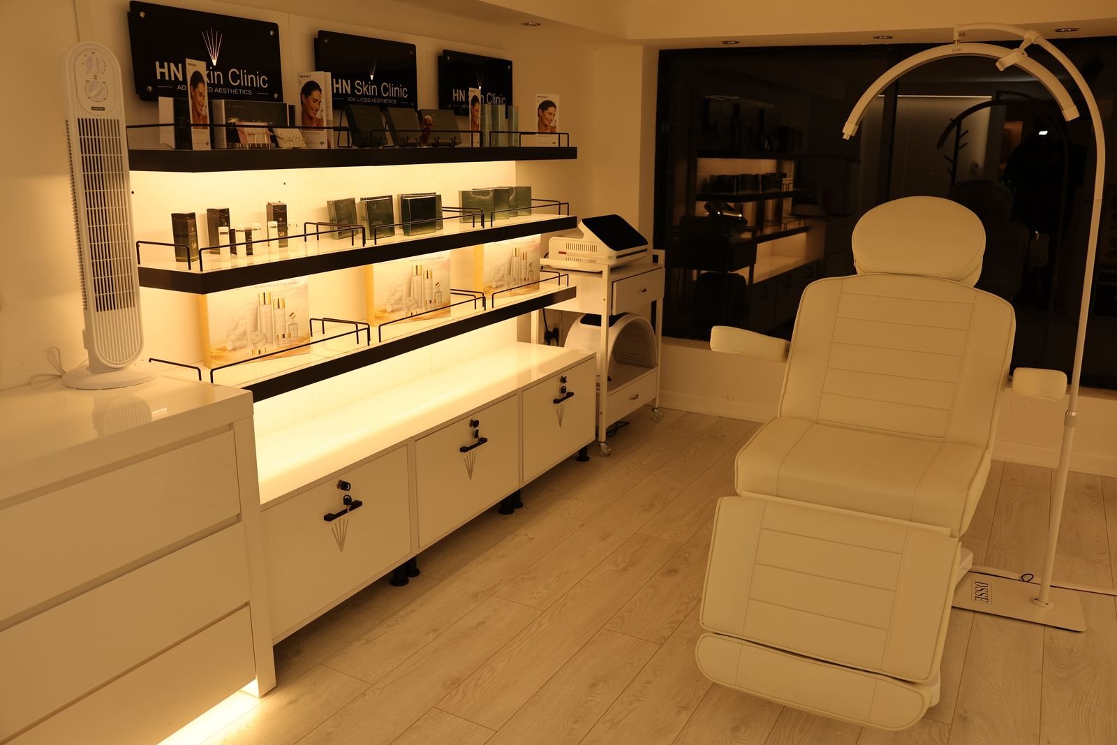 HN Skin Clinic treatment room with branded shelves and treatment chair